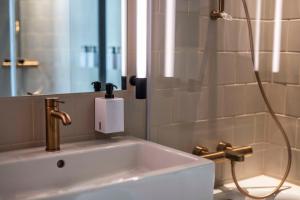 a bathroom with a sink with a shower and a mirror at Scandic Kødbyen in Copenhagen