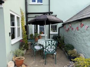 a patio with a table and chairs and an umbrella at Pelican House in Bridport