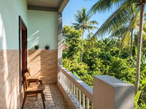 Ein Balkon mit einem Stuhl und Bäumen in der Unterkunft Buana Asti Homestay Retreat Batukaru in Tabanan
