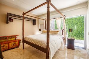 a bedroom with a four poster bed and a window at Magia Beachside Condo in Playa del Carmen +43 photos