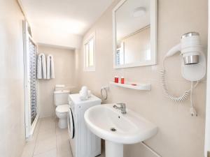a white bathroom with a sink and a toilet at Apartamentos El Faro By Mc in Benidorm