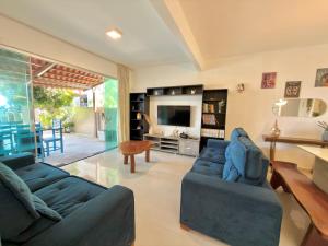 a living room with two blue couches and a television at Brisa de Barra Grande Beach House Pé na Areia in Maragogi