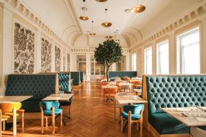 a dining room with tables and blue booths at Hôtel Miléade L'Orangeraie - entièrement rénové in Menton