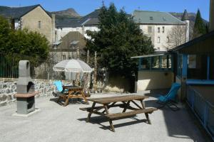 a patio with two picnic tables and an umbrella at Villa des Familles La Bourboule in La Bourboule