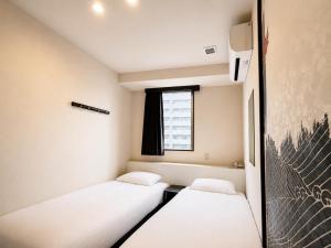 two beds in a small room with a window at Hotel Arashi Namba No001 in Osaka +46 photos
