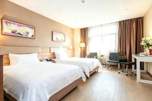 a hotel room with two beds and a desk at Dayi Yihao hotel in Xiamen