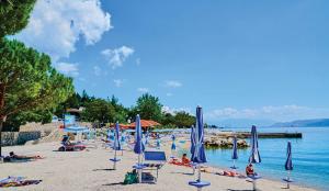 a beach with blue umbrellas and people in the water at Maslina in Crikvenica