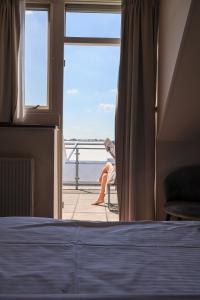 a woman sitting in a chair looking out a window at the ocean at Moeke Mooren in Appeltern