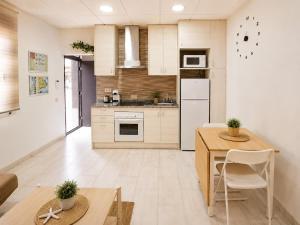 a kitchen with white cabinets and a table and chairs at EL Niu del Delta in Deltebre