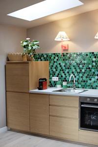 a kitchen with a sink and a green wall at Moft Loft. Lovely, comfy apartment. in Cluj-Napoca