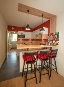 a kitchen with red walls and two bar stools at La Villa du Sillon by les Ambassadeurs - Saint Malo Plage in Saint Malo
