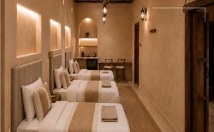 a hotel room with three beds in a room at Nomad Inn Al Bustan in Nizwa