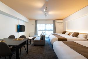 a hotel room with four beds and a table and chairs at Residence Hotel KABUTO Premier in Sapporo
