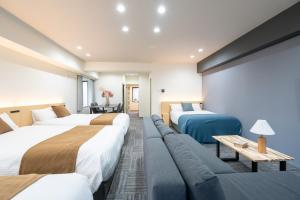 a hotel room with three beds and a couch at Residence Hotel KABUTO Premier in Sapporo