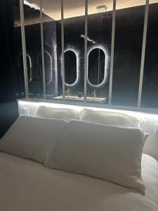a bed with white pillows in a room with windows at La Nuit Etoilee Balneo Hyper Centre Chalon in Chalon-sur-Saône