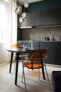 a kitchen with a table and chairs and a sink at La Nuit Etoilee Balneo Hyper Centre Chalon in Chalon-sur-Saône