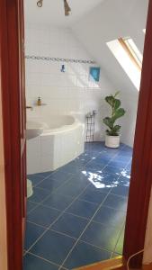 a bathroom with a blue tiled floor and a tub and a plant at Winterberg Vendégház in Óbánya +20 photos