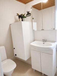 a white bathroom with a sink and a toilet at Villa Ralli in Jämsä