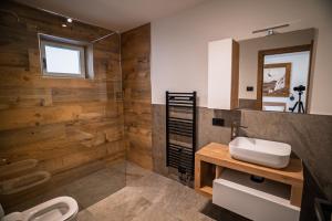 a bathroom with wooden walls and a sink and a toilet at La Stua de Anny by AMA Val di Fassa in Pozza di Fassa +9 photos