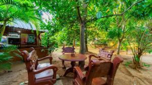 a table and chairs in a yard with trees at Sayare Inn in Dambulla