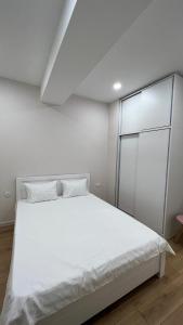 a white bedroom with a large bed with white sheets at 21 floor apartment in Tbilisi City