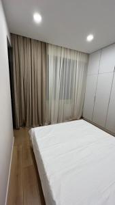 a bedroom with a large white bed in front of a window at 21 floor apartment in Tbilisi City +7 photos
