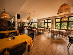 a restaurant with tables and chairs and windows at Pensjonat Pod Jemiołą in Ciechocinek