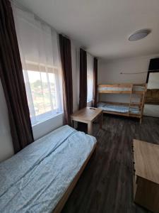a bedroom with two beds and a desk and a window at Kitti Panzió in Tiszadada +28 photos