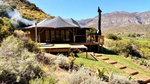 a house on a hill with mountains in the background at Ontevreden Farm in Montagu