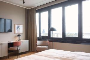 a hotel room with a bed and a desk and windows at Scandic München Macherei in Munich