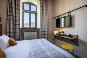 a hotel room with a bed and a tv at DAFFY Hôtel in Briançon +15 photos