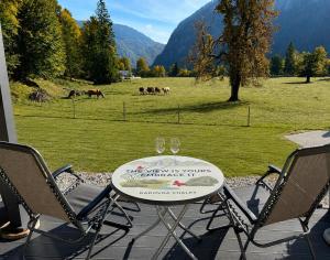 a table with two wine glasses and a field of horses at Radovna Chalet with Panoramic View in Mojstrana +12 photos