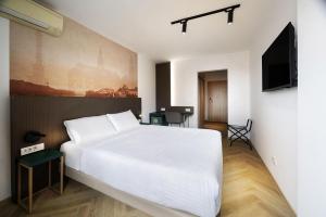 a bedroom with a white bed and a flat screen tv at B&B HOTEL Maribor Orel in Maribor