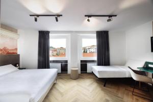 a bedroom with two beds and two windows at B&B HOTEL Maribor Orel in Maribor