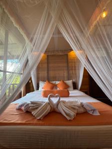 a bedroom with a canopy bed with orange pillows at Saffron Eco Cottage in Ella