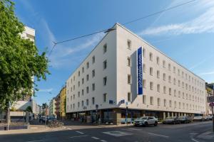 a white building with a blue sign on it on a street at a&o Köln Neumarkt in Cologne