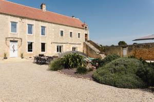a building with a table and chairs in front of it at L'écrin des quatre puits in Cesny-aux-Vignes