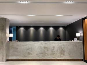 a person standing behind a counter in a lobby at Houi Hotel in Jodoh