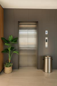 a metal elevator door with a potted plant at Houi Hotel in Jodoh