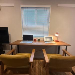 two laptops sitting on a wooden table with chairs at Sunlife in Sendai