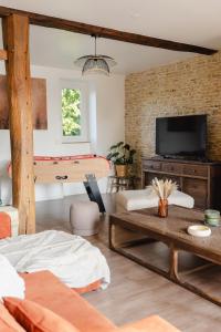a living room with a couch and a tv at L'écrin des quatre puits in Cesny-aux-Vignes