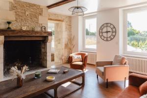 a living room with a fireplace and a table and chairs at L'écrin des quatre puits in Cesny-aux-Vignes