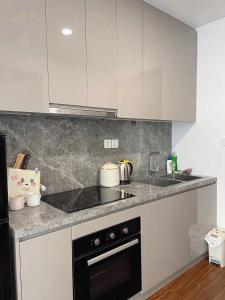 a kitchen with white cabinets and a sink and a stove at Bảo Châm Homestay in Gia Lâm Pho