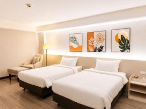 a hotel room with two beds and a chair at Miloft Suvarnabhumi Airport Hotel in Lat Krabang