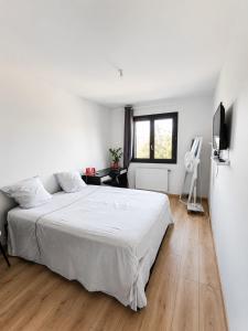 a white bedroom with a bed and a television at Beautiful, modern room in Saint-Paul-de-Varax