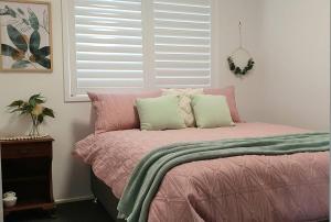 a bedroom with a pink bed with pillows and a window at Marigold House in Rockville