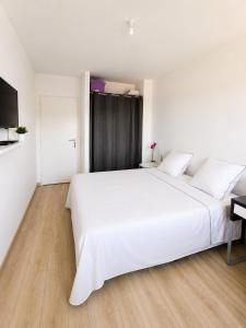 a white bedroom with a large white bed and a desk at Beautiful, modern room in Saint-Paul-de-Varax