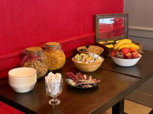 a table with bowls of fruit and other foods on it at Logis Hôtel des Remparts - Saint-Lô in Saint Lo
