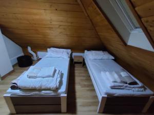 two beds in a attic room with wooden ceilings at LŰN Apartman in Dunaföldvár