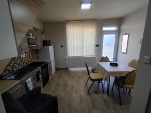 a kitchen and dining room with a table and a table and chairs at LŰN Apartman in Dunaföldvár